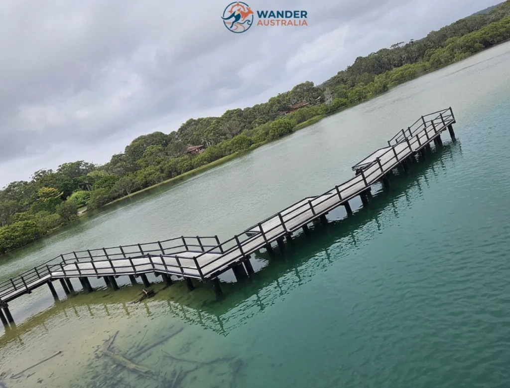 Wooden boardwalk crossing calm estuary waters near Back Beach image